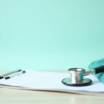 Stethoscope, clipboard and medical scrubs on a clean desk