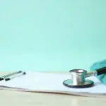Stethoscope, clipboard and medical scrubs on a clean desk